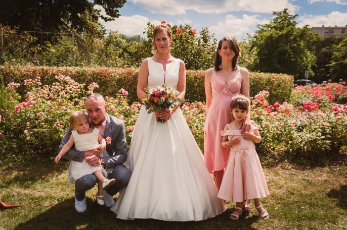 Une mariée posant avec sa famille dans un jardin fleuri, sourires et robes élégantes.