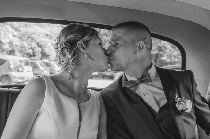 Un couple s'embrassant à l'intérieur d'une voiture, en noir et blanc.
