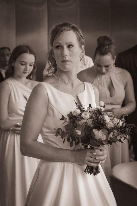 Mariée en robe blanche avec un bouquet, entourée de demoiselles d'honneur.