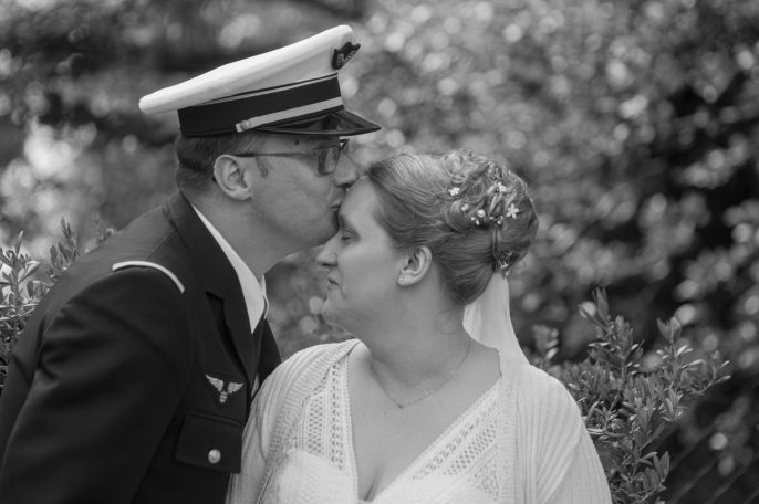 Un couple en tenue de mariage, avec l'homme en uniforme militaire et la femme en robe blanche.